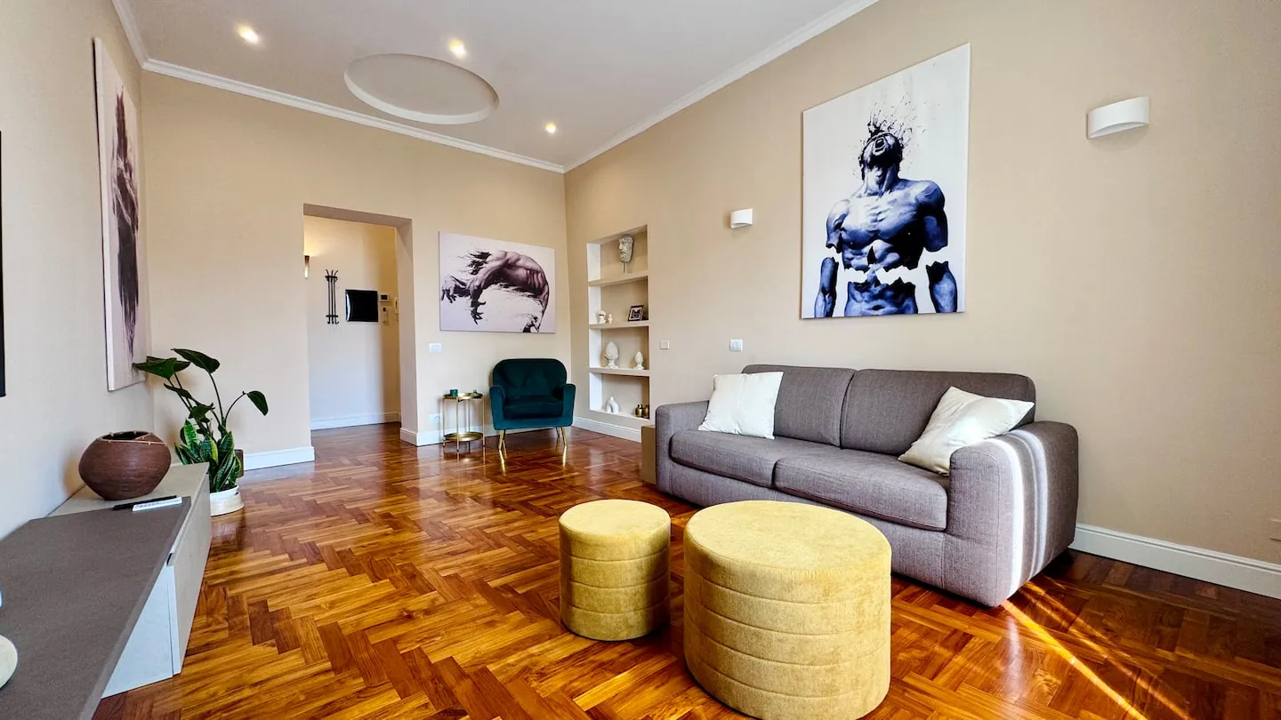 Soggiorno open space con divano e parquet in teak